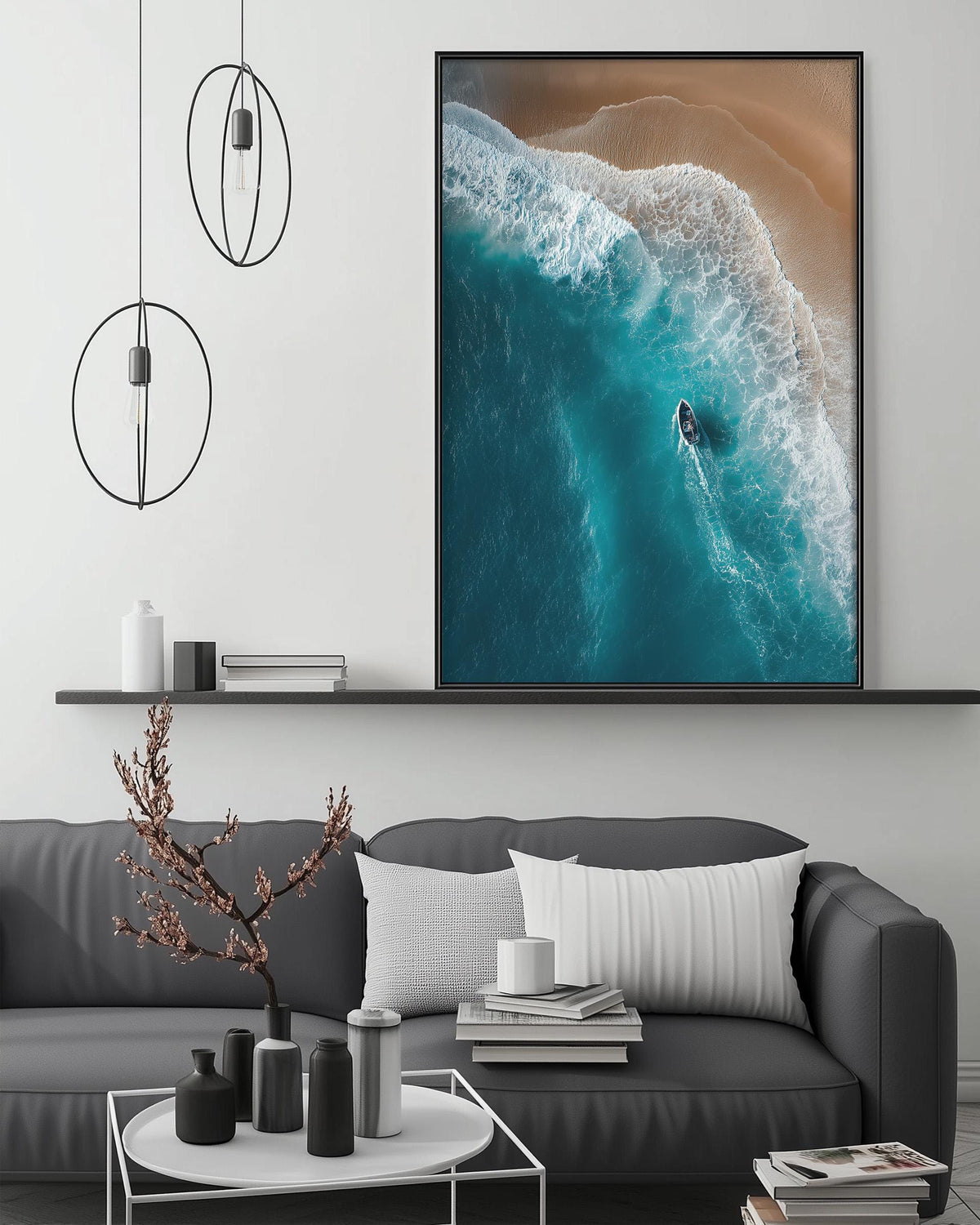 a large, square, black and white photograph of a surfer riding a wave, hanging on a wall above a gray couch with white pillows.
