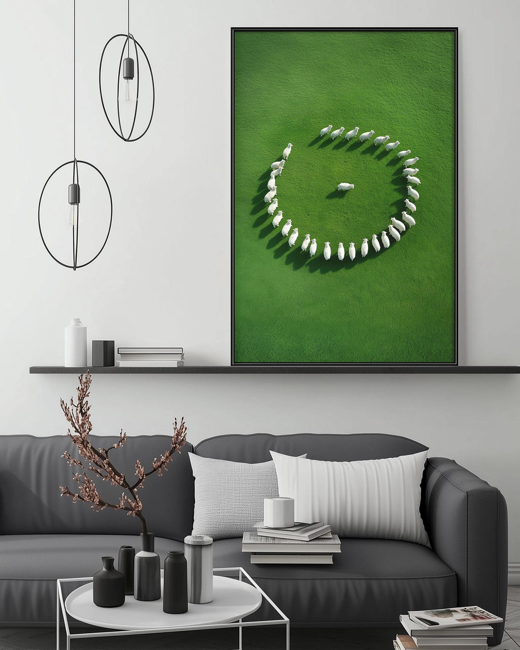 a modern living room with a gray sofa, a coffee table, and a large framed artwork depicting a herd of sheep arranged in a circular pattern on a green field.