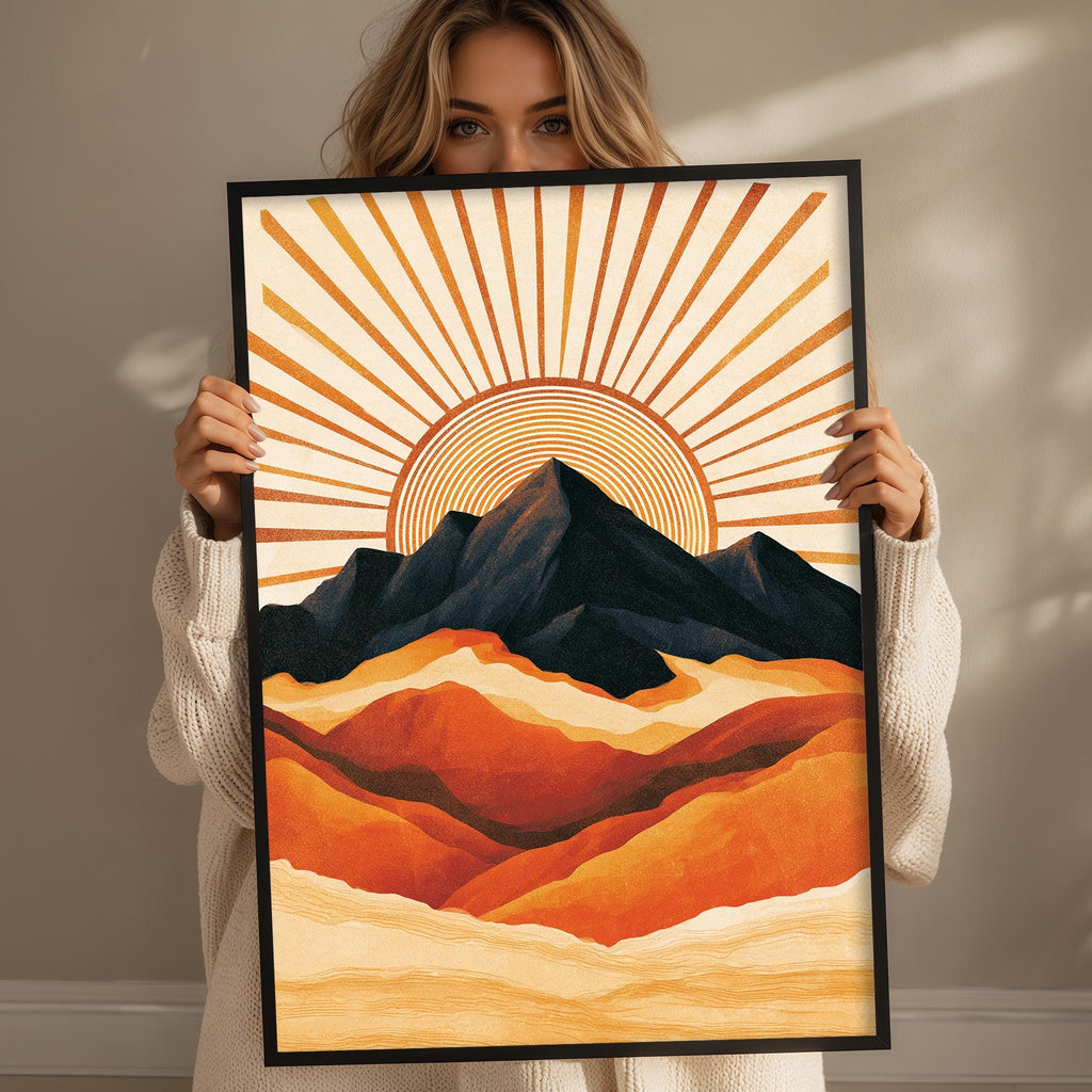 A woman holds up a framed print of a vibrant mountain landscape with a sunburst design.