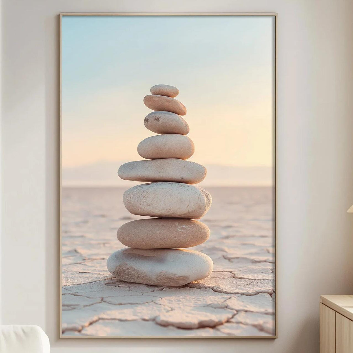 a large framed picture of a stack of stones on a beach, with a warm sunset in the background.