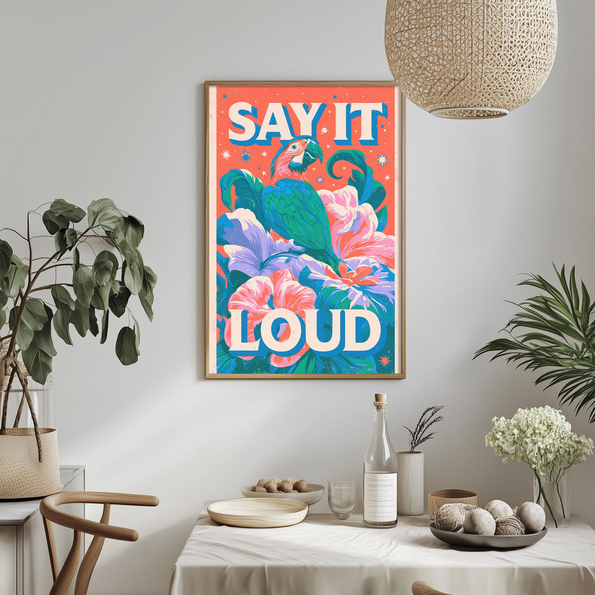 a vibrant poster with a tropical bird and colorful flowers, hanging on a wall above a dining table with various decorative items and plants.