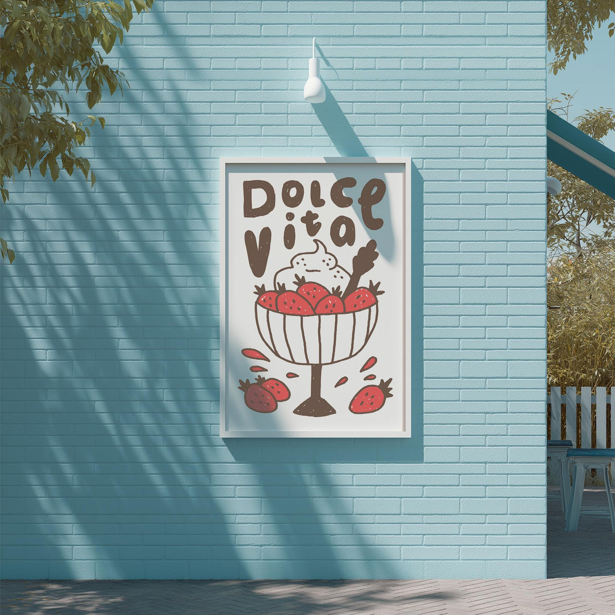 a poster with a blue background and a white frame, hanging on a wall. The poster has a drawing of a bowl of strawberries and cream, along with the text "Dolce Vita" written above it.