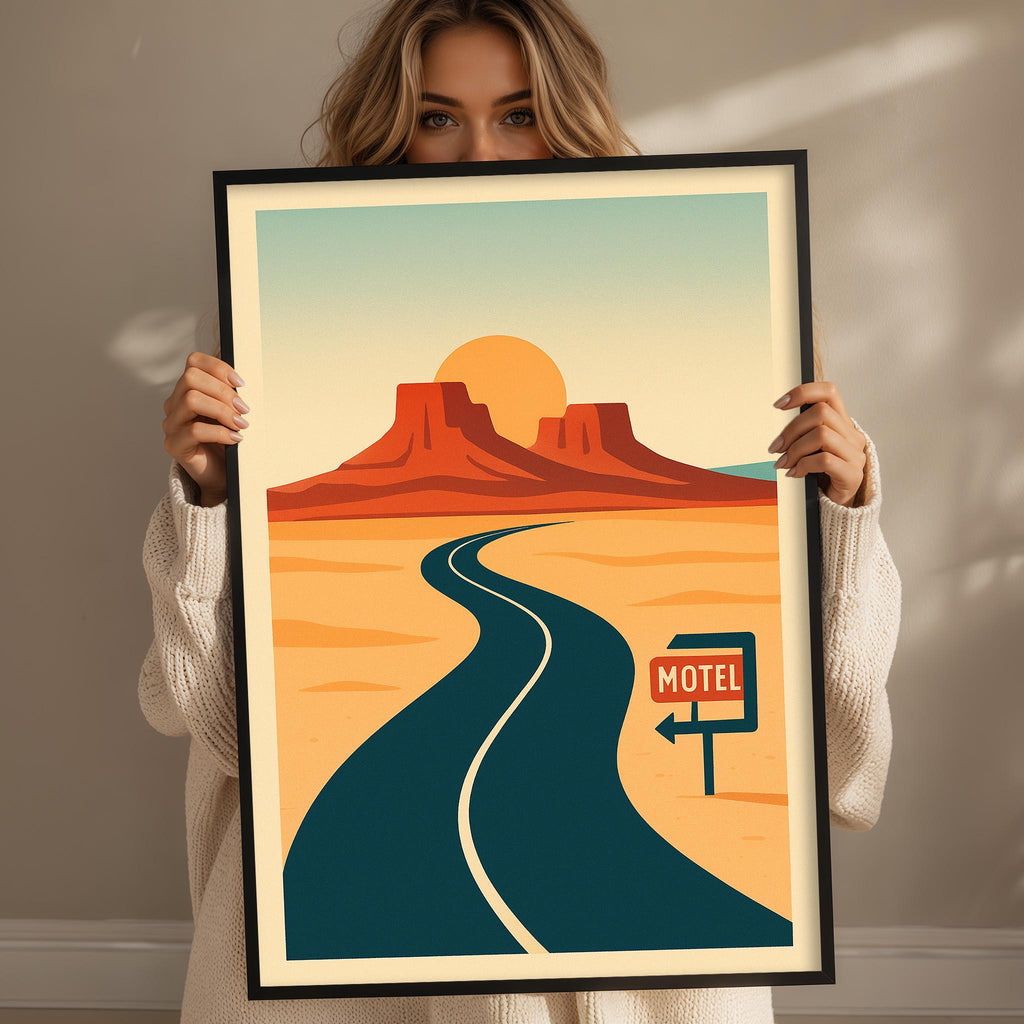 A woman is holding up a framed poster of a desert landscape with a road leading to a motel sign.