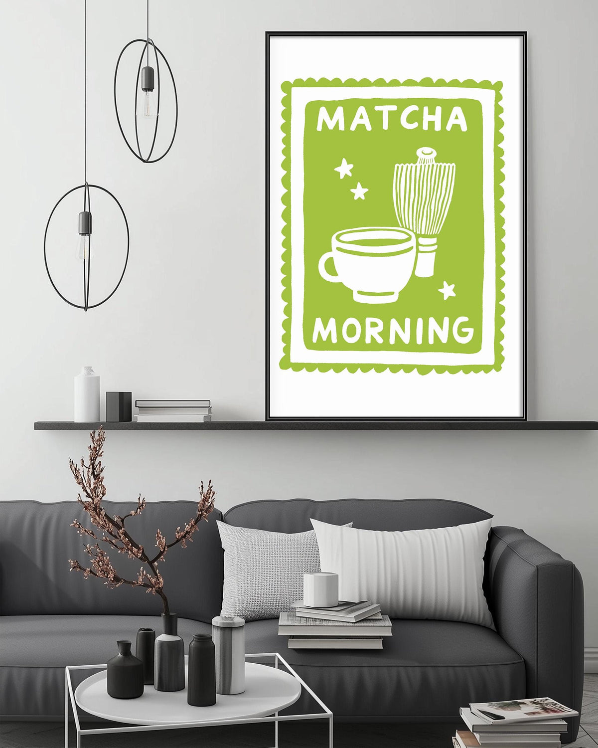 a living room with a gray couch, a coffee table, and a framed poster on the wall that says "MATCHA MORNING".