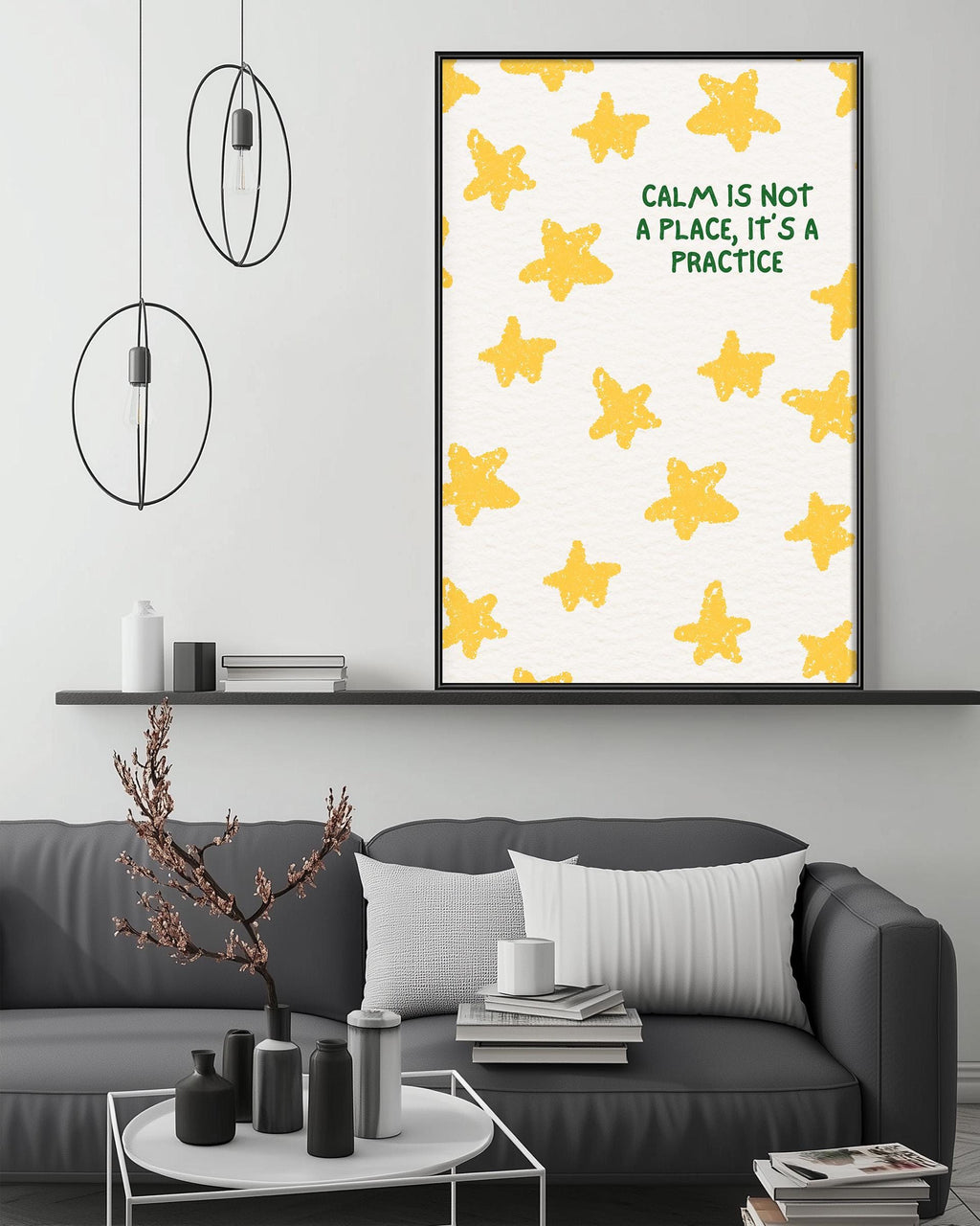 a living room with a gray couch, a coffee table, and a framed poster with a yellow star pattern and the text "Calm is not a place, it's a practice" above it.