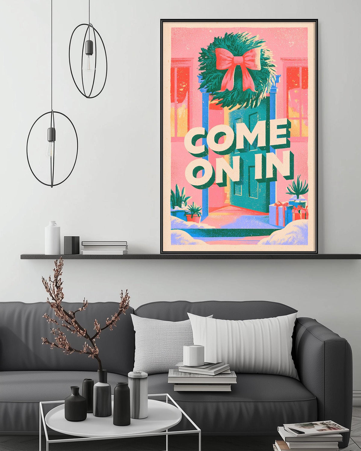 a cozy living room with a gray couch, a coffee table, and a large framed poster hanging on the wall. The poster has a festive design with a wreath and the text "COME ON IN" displayed prominently.