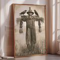 A framed black and white photograph depicting a scarecrow standing in a field, with two birds perched on its back.