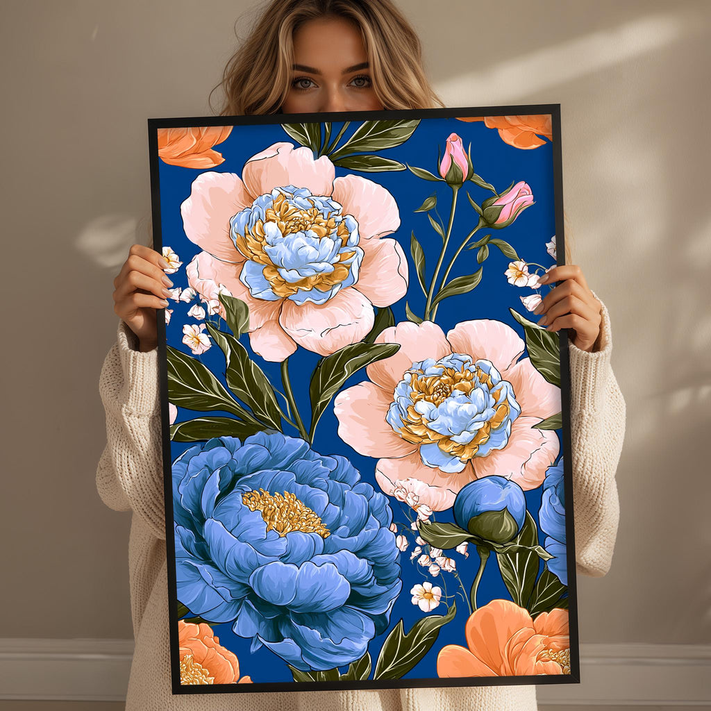 A woman is holding up a framed print with a vibrant floral design featuring blue, pink, and orange flowers against a blue background.