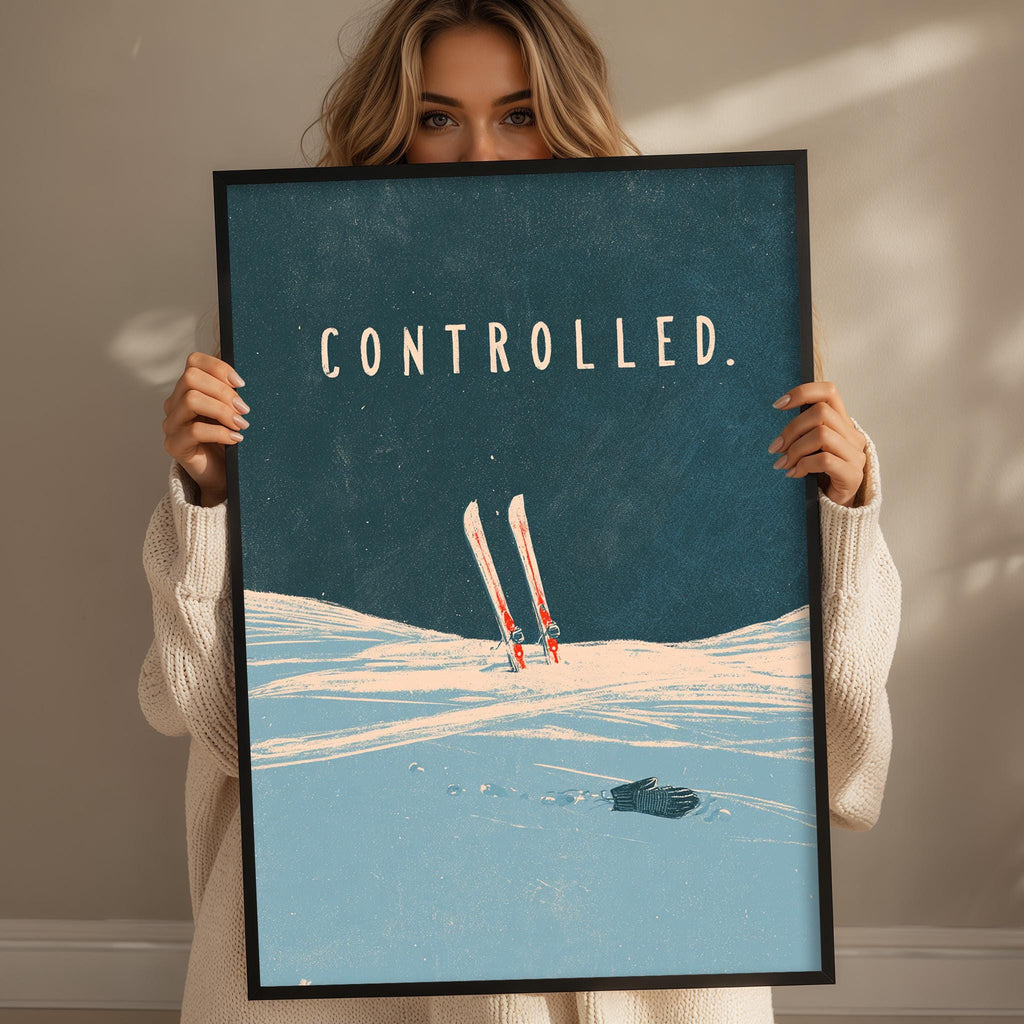 A woman holding a framed poster with a skiing scene and the word "controlled" written on it.