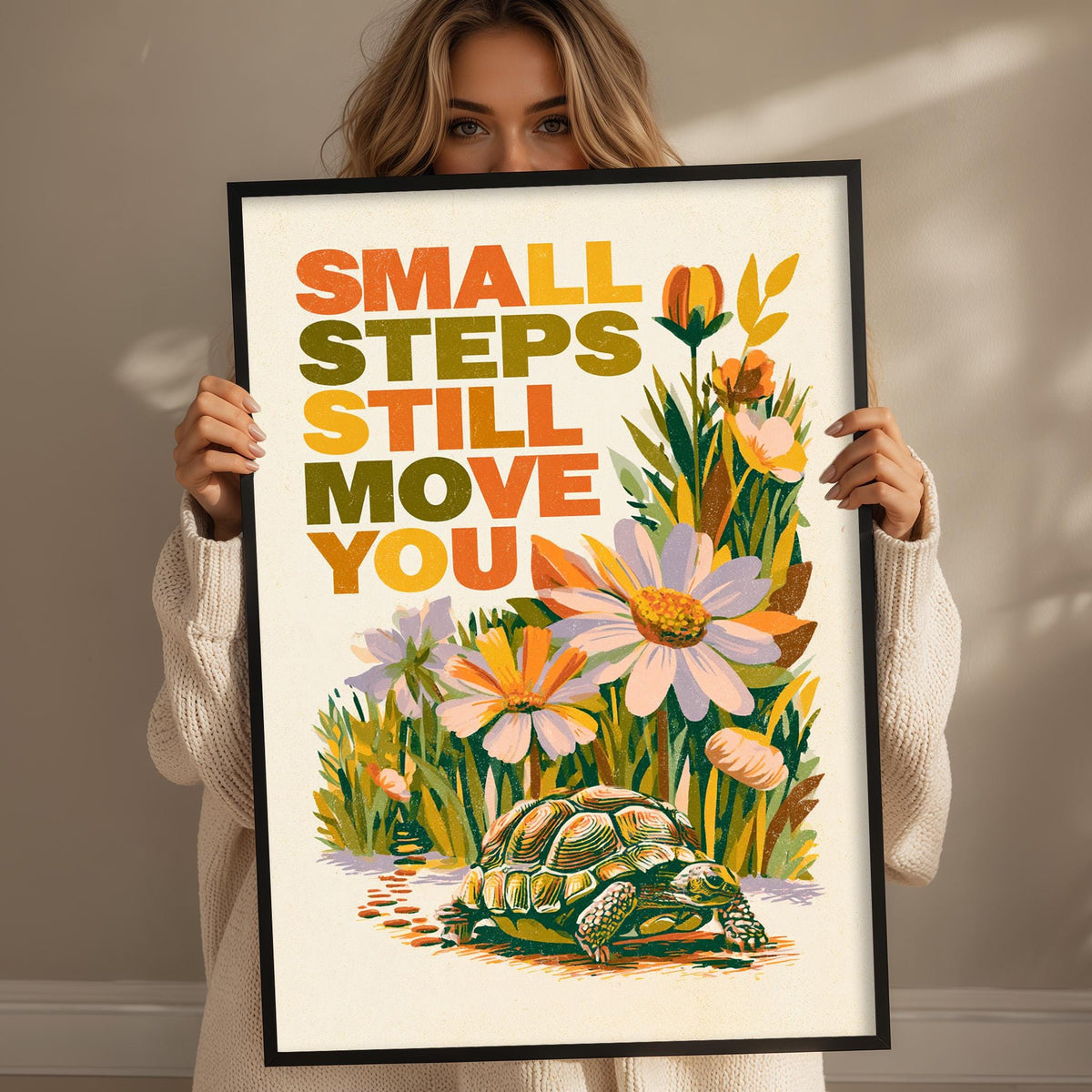 A woman holding a framed poster with a colorful illustration of a turtle and flowers.