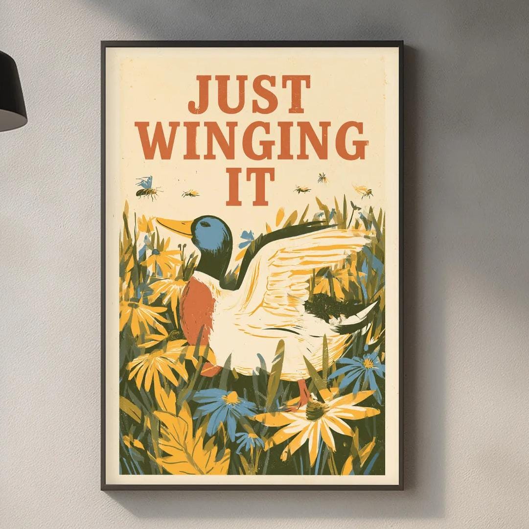 a framed poster with a duck and flowers hanging on a wall above a kitchen counter.