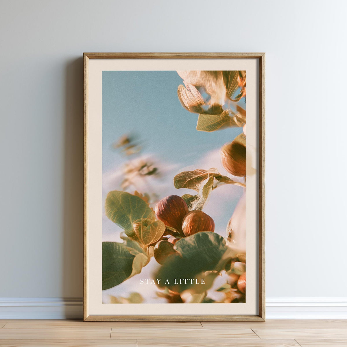 The image is a framed print of a close-up of a plant with leaves and fruits, set against a blurred background of a blue sky.