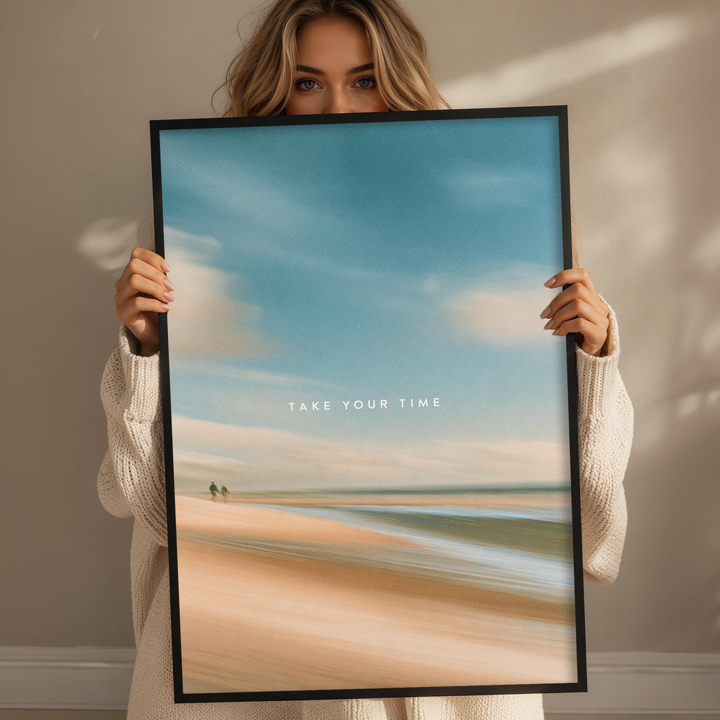 A woman holding a framed picture of a beach scene with the text "TAKE YOUR TIME" on the bottom of the frame.
