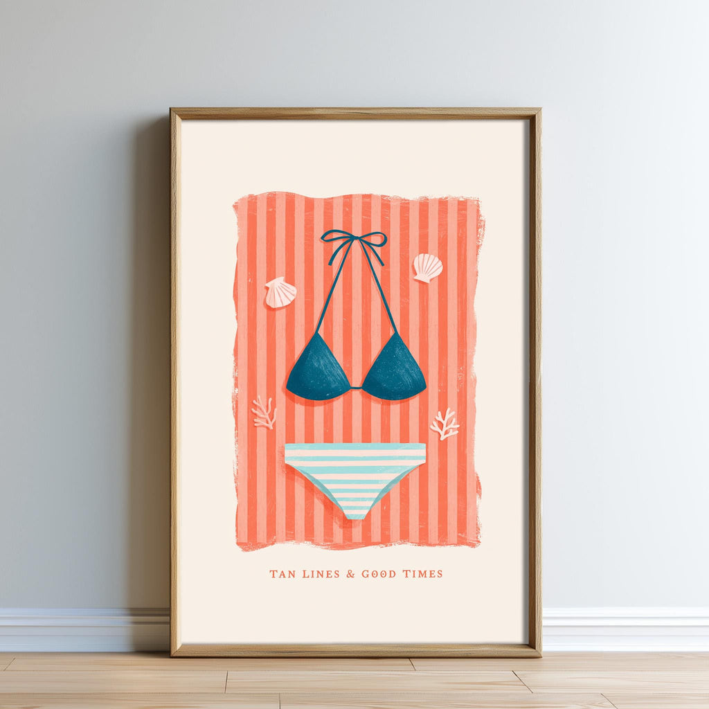 A framed illustration of a bikini top and bottoms against a striped background, accompanied by the text "TAN LINES & GOOD TIMES".