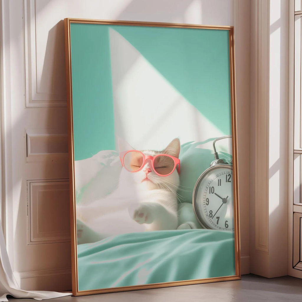 A framed image of a cat wearing pink sunglasses, lying on a bed next to a clock.