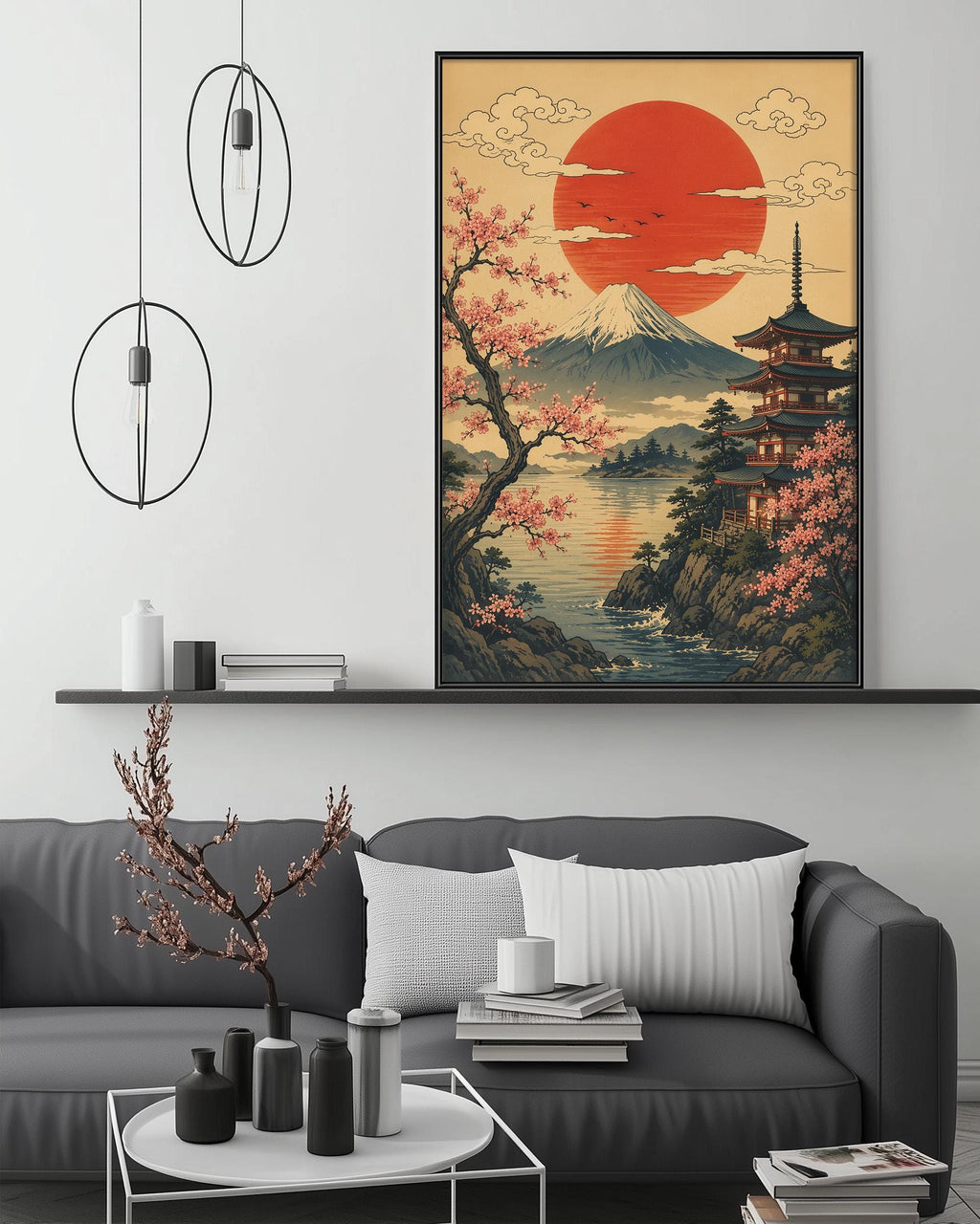 a large framed artwork depicting a serene Japanese landscape with a temple, cherry blossoms, and a red sun in the sky. The artwork is hung on a wall above a gray couch, which is adorned with a small tree and various decorative items. The overall setting appears to be a cozy and inviting living space.