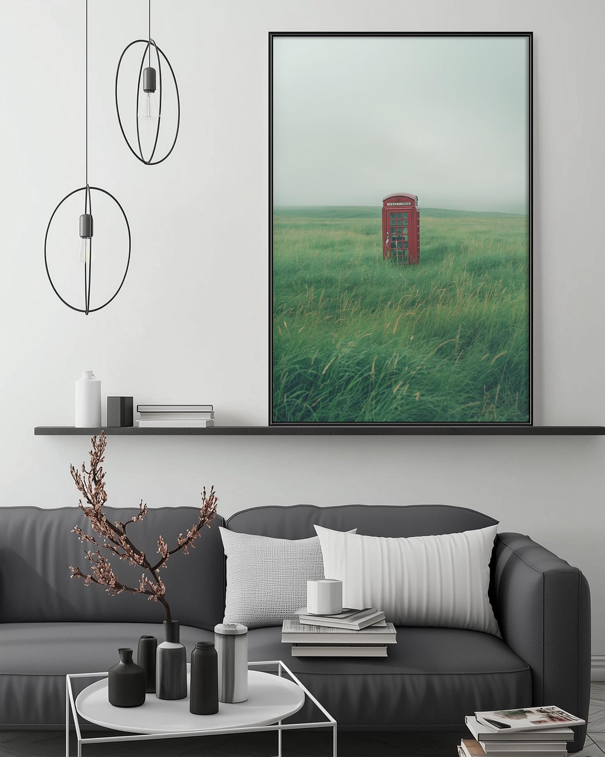 a large framed picture of a red telephone booth in a grassy field, hanging on a wall above a gray couch with a coffee table in front of it.