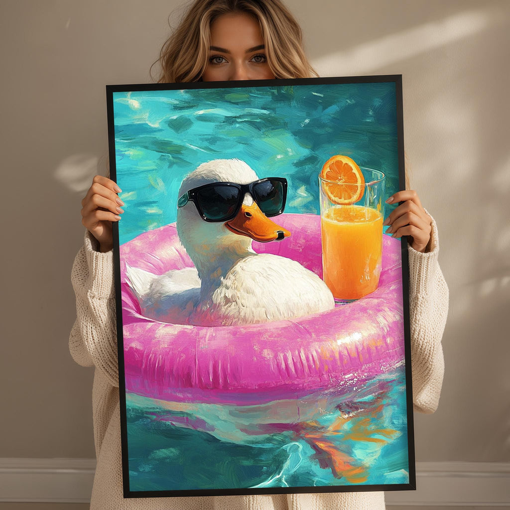 A woman holds up a framed painting depicting a duck wearing sunglasses and floating on a pink inner tube, with a glass of orange juice nearby.