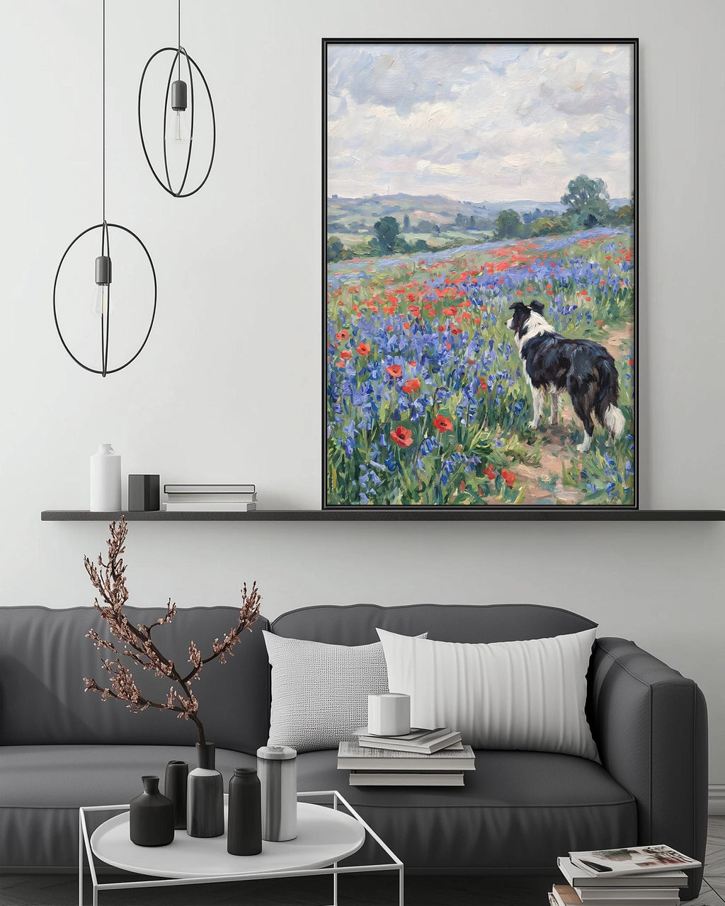 a large painting of a dog standing in a field of flowers, with a black and white border. The painting is hanging on a wall above a gray couch, which has a coffee table in front of it. The room also has a shelf with various decorative items, and a potted plant on the floor.