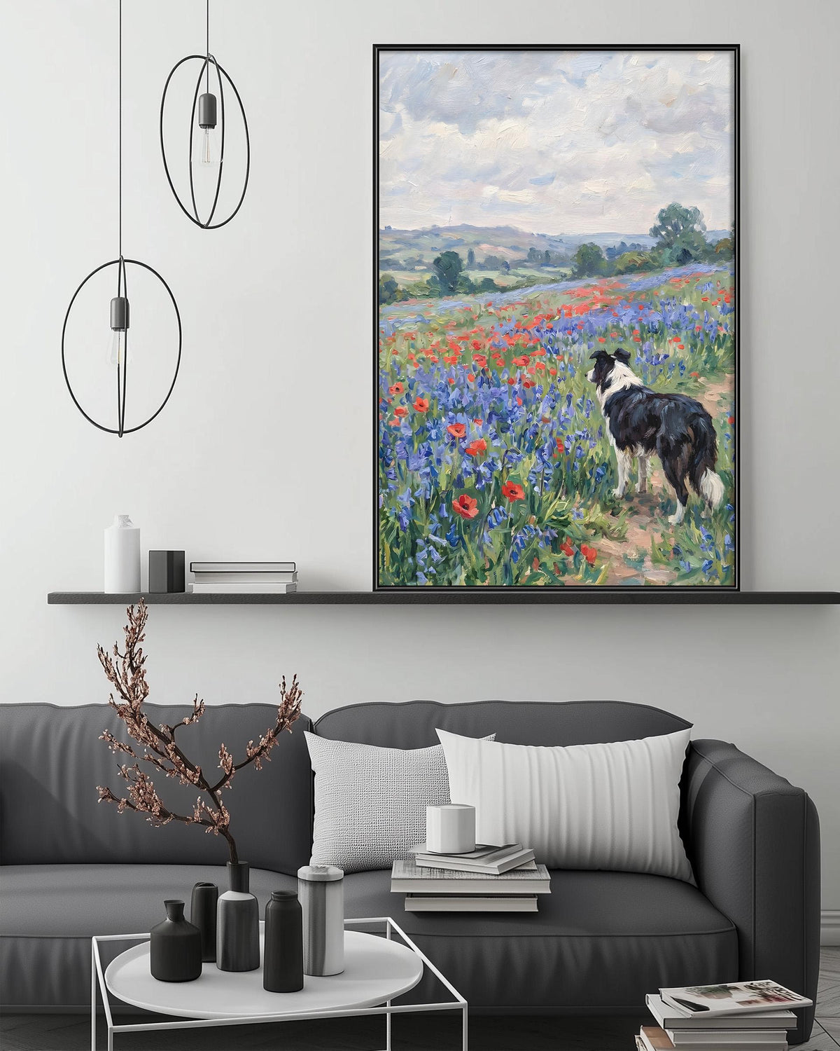 a large painting of a dog standing in a field of flowers, with a black and white border. The painting is hanging on a wall above a gray couch, which has a coffee table in front of it. The room also has a shelf with various decorative items, and a potted plant on the floor.