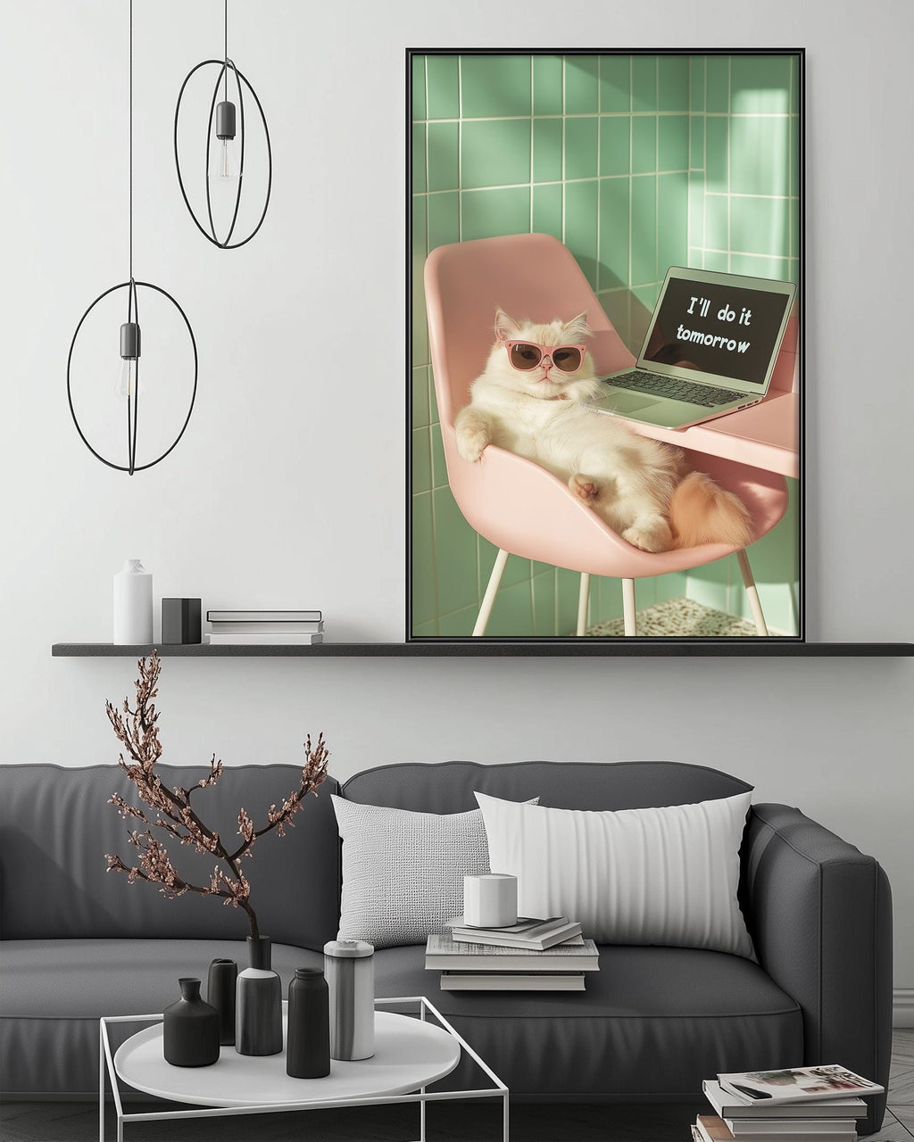 A white cat wearing sunglasses is sitting on a pink chair, with a laptop on the chair's surface, in a modern living room setting with a gray couch, a coffee table, and a framed picture on the wall.