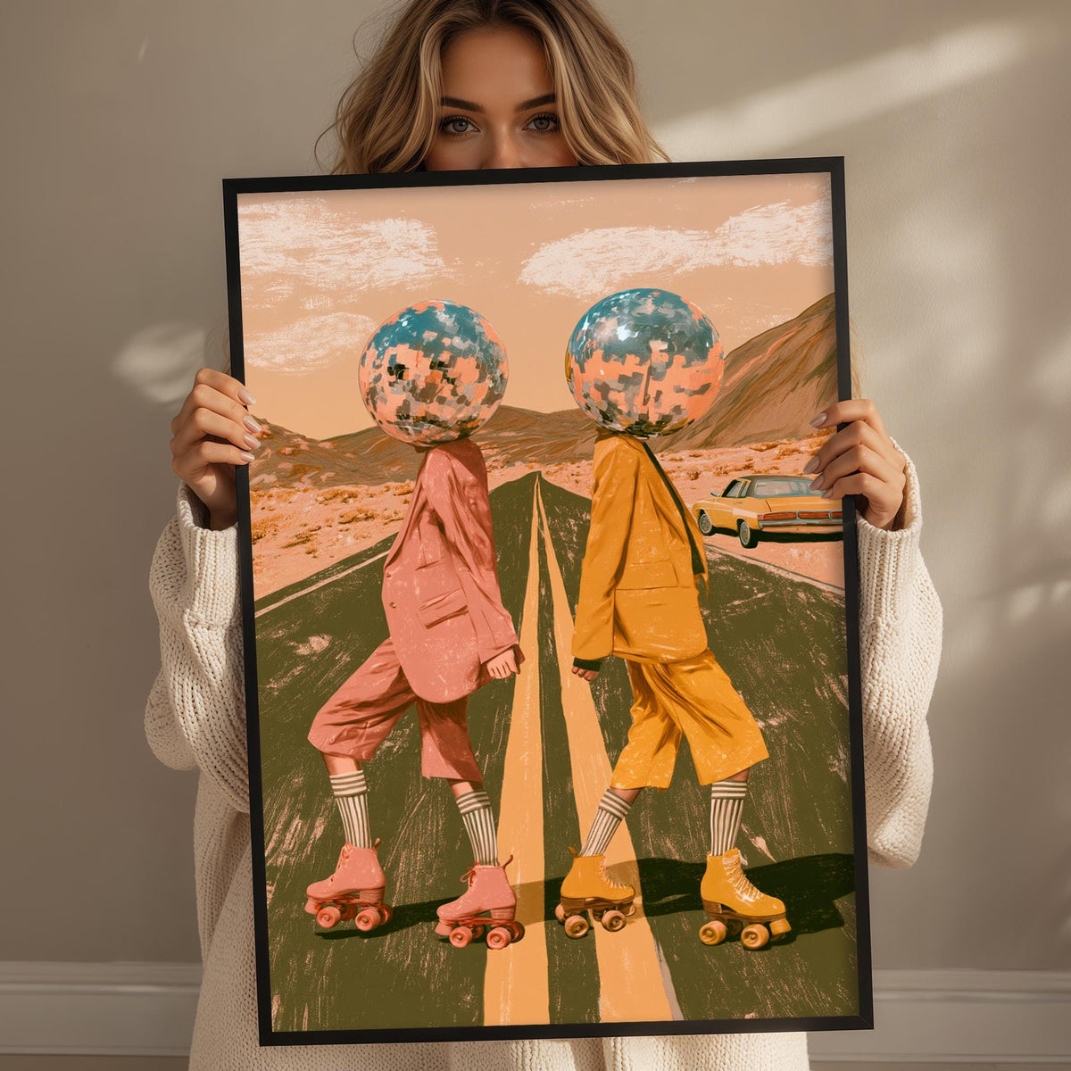 A woman holds up a framed image depicting two people on rollerblades, with one wearing a pink outfit and the other in an orange outfit, against a desert landscape with mountains in the background.