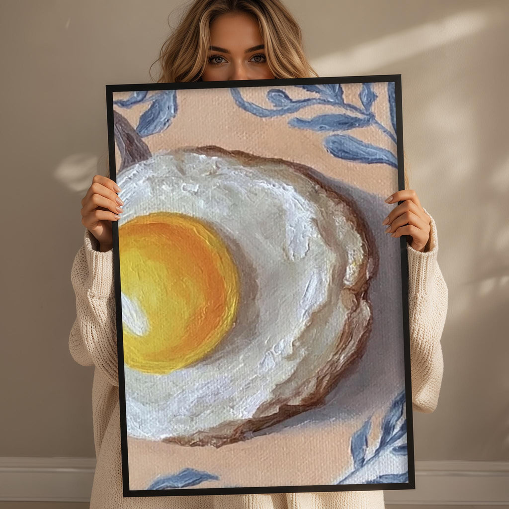 A woman holds up a framed painting of an egg on a light brown background with blue floral elements.