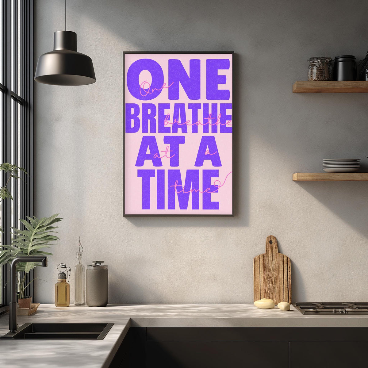a kitchen counter with a framed poster that reads "ONE BREATHE AT A TIME" in purple text. The poster is hanging on a wall above the counter.