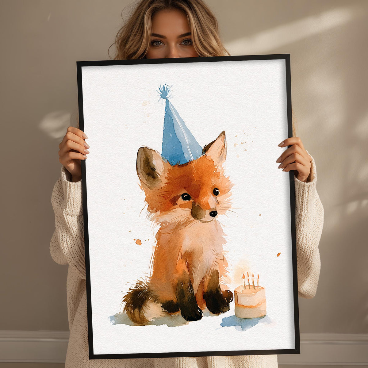 A woman is holding up a framed watercolor painting of a fox wearing a birthday hat and sitting next to a birthday cake.
