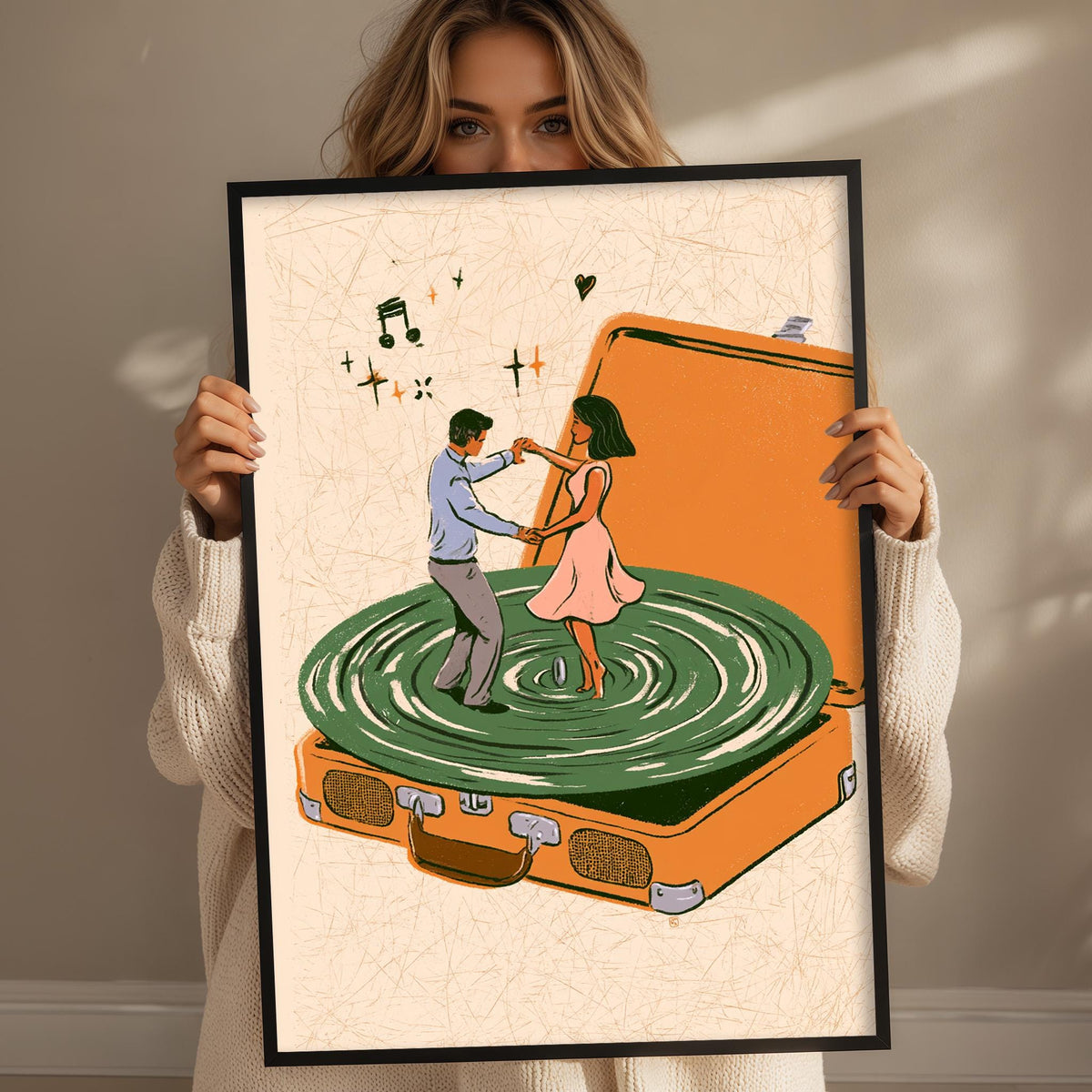 A woman holds up a framed illustration depicting a man and a woman dancing on a turntable.