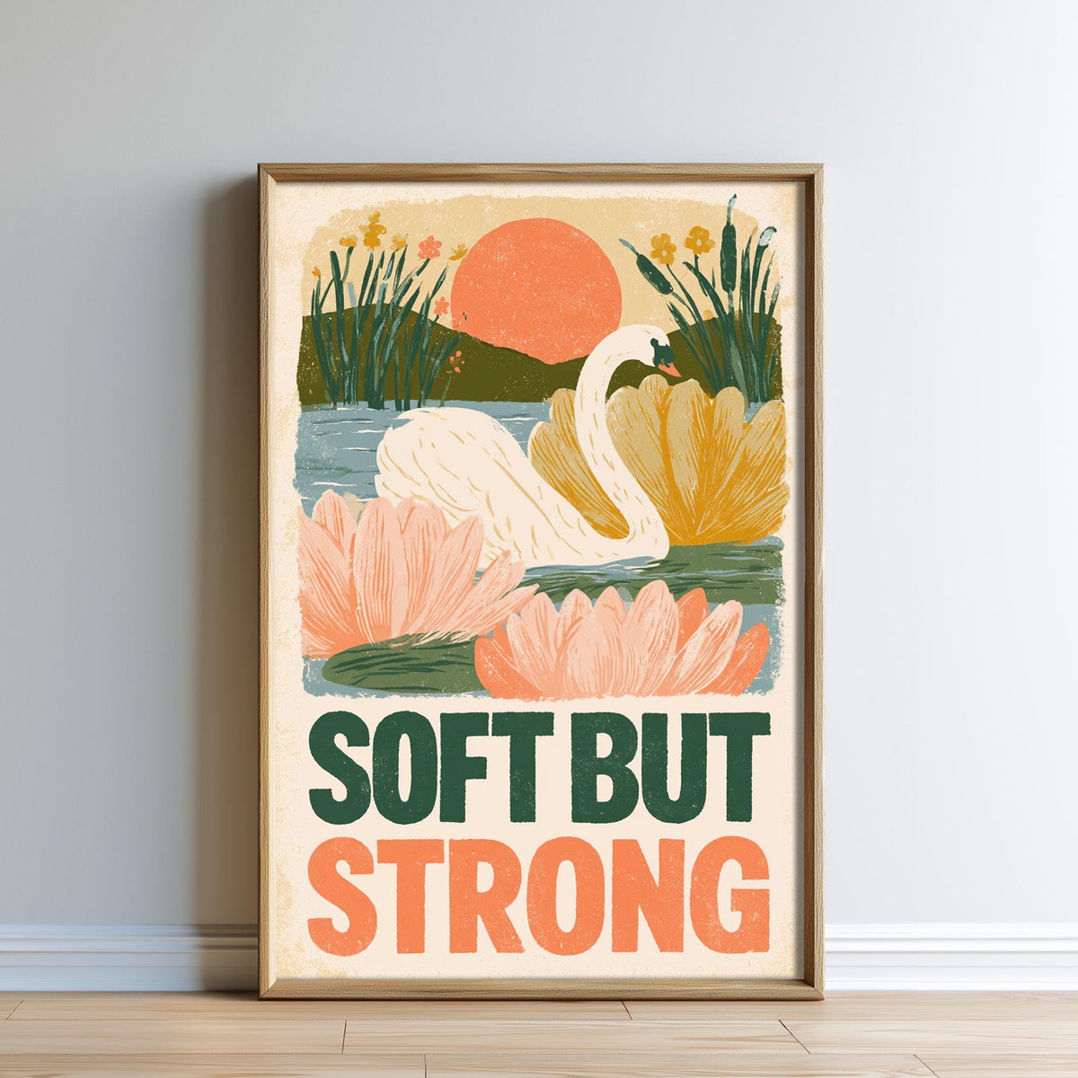 The image is a framed poster with a colorful illustration of a swan, flowers, and a sunset. The text on the poster says "Soft but Strong".