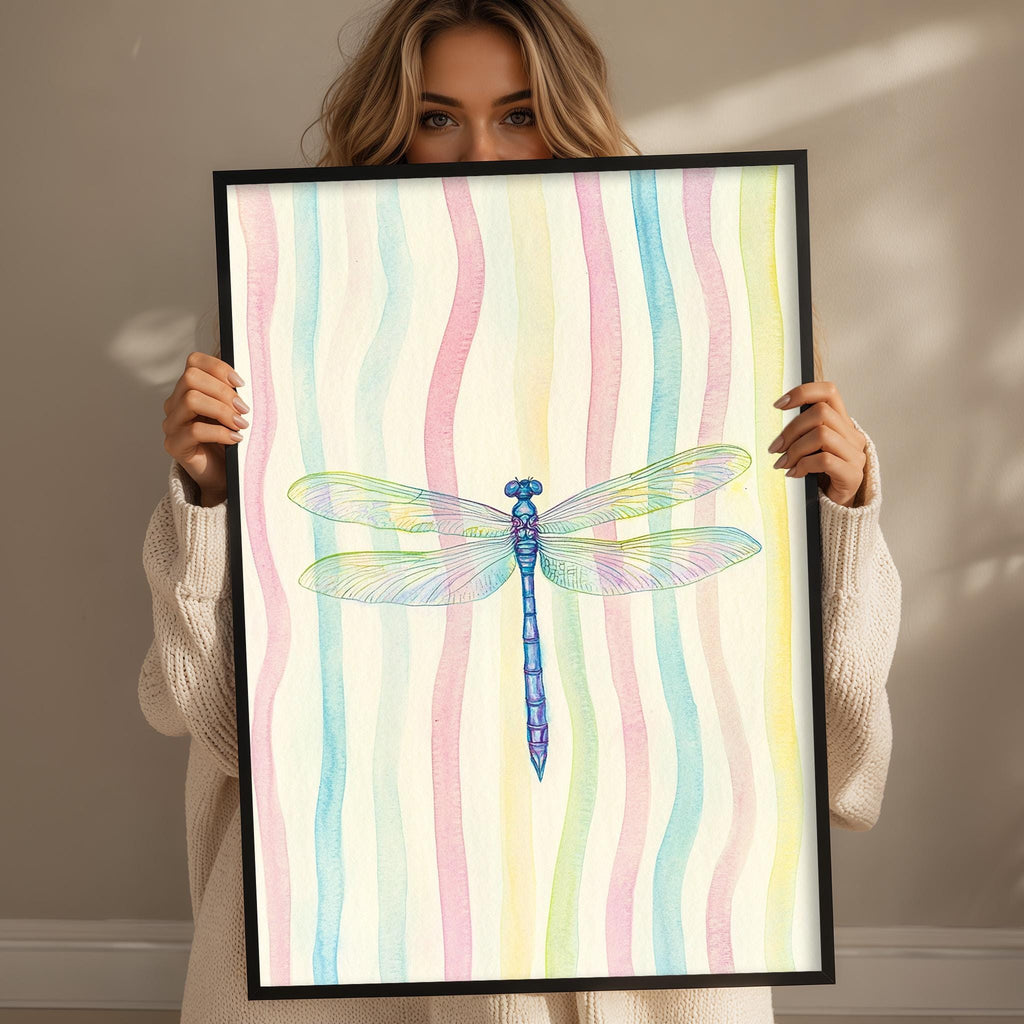 A woman is holding up a framed picture of a colorful dragonfly.