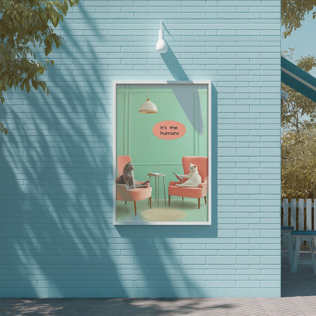 A framed poster on a blue wall depicting two cats sitting in chairs, with one cat appearing to be reading a book.