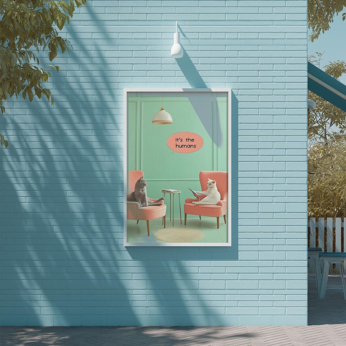 A framed poster on a blue wall depicting two cats sitting in chairs, with one cat appearing to be reading a book.