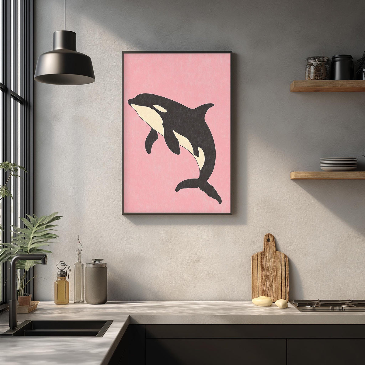 a kitchen counter with various items, including a framed picture of a black and white orca whale, a wooden cutting board, and a potted plant.