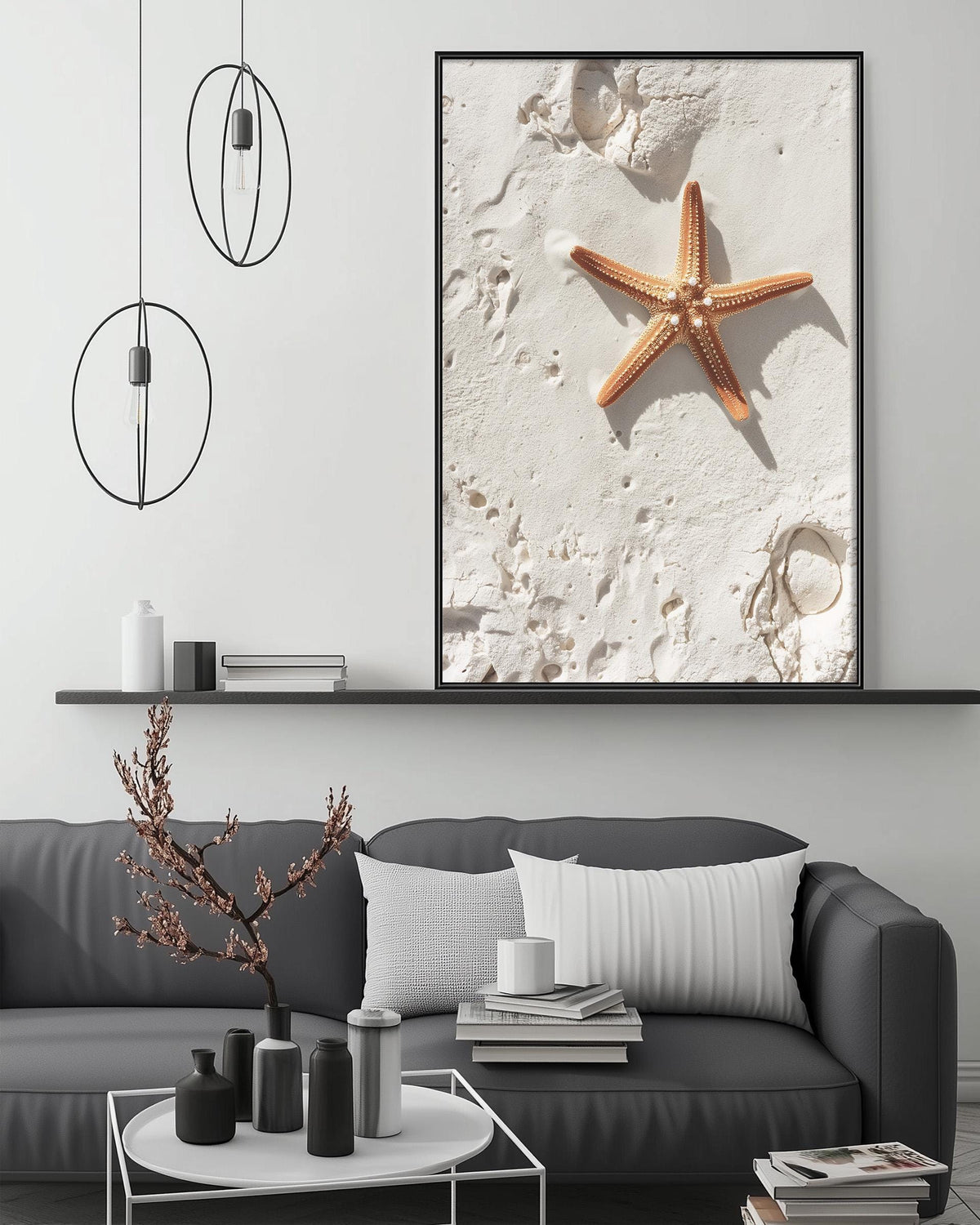 a large framed photograph of a starfish on a white surface, hanging on a wall above a gray couch with a coffee table in front of it.