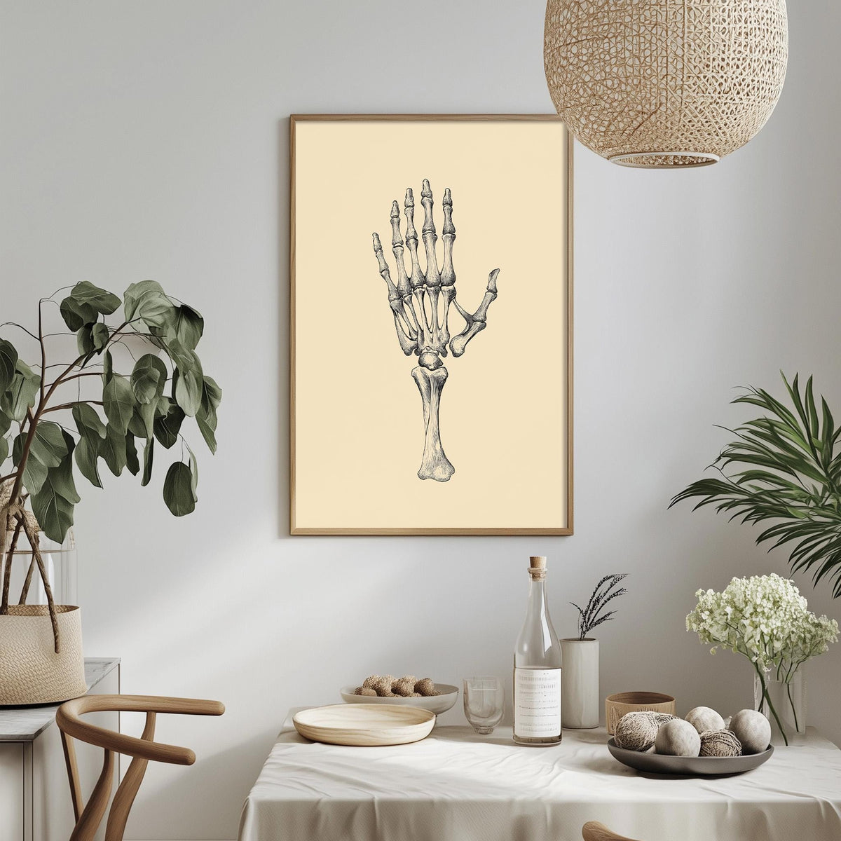 a dining table with a bowl of fruit, a bottle, and a vase of flowers, along with a framed illustration of a human hand on the wall.