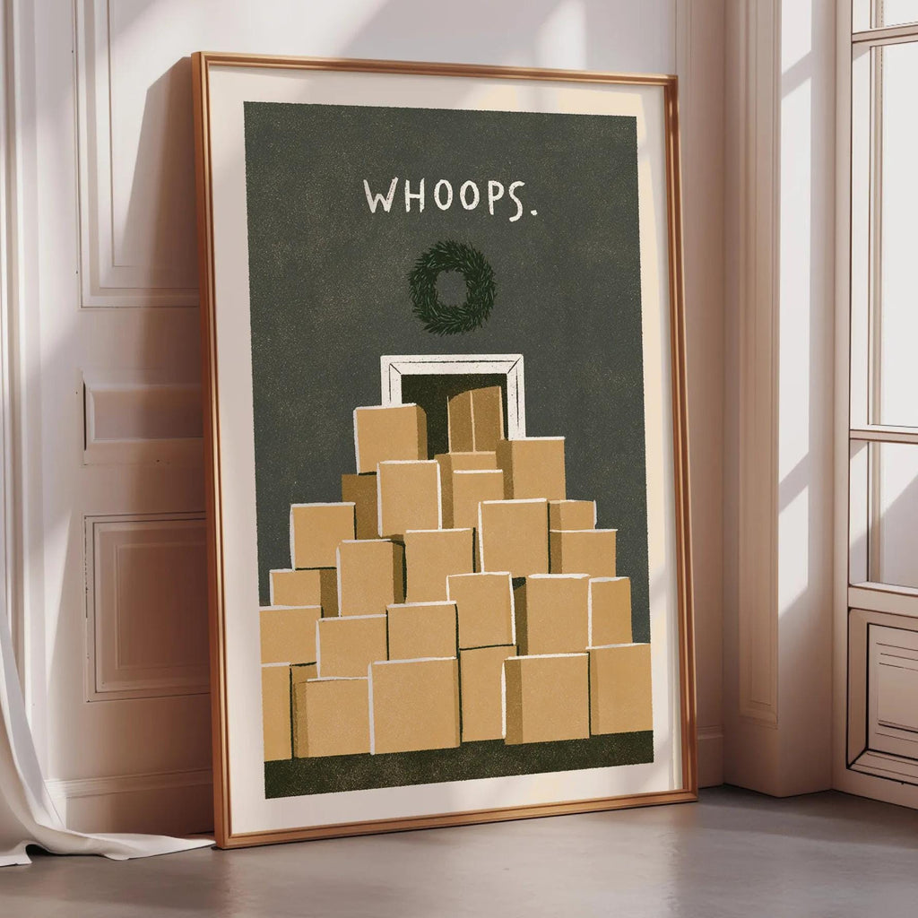 A framed poster with a wreath and the text "WHOOPS" on it, placed on a wooden floor next to a window.