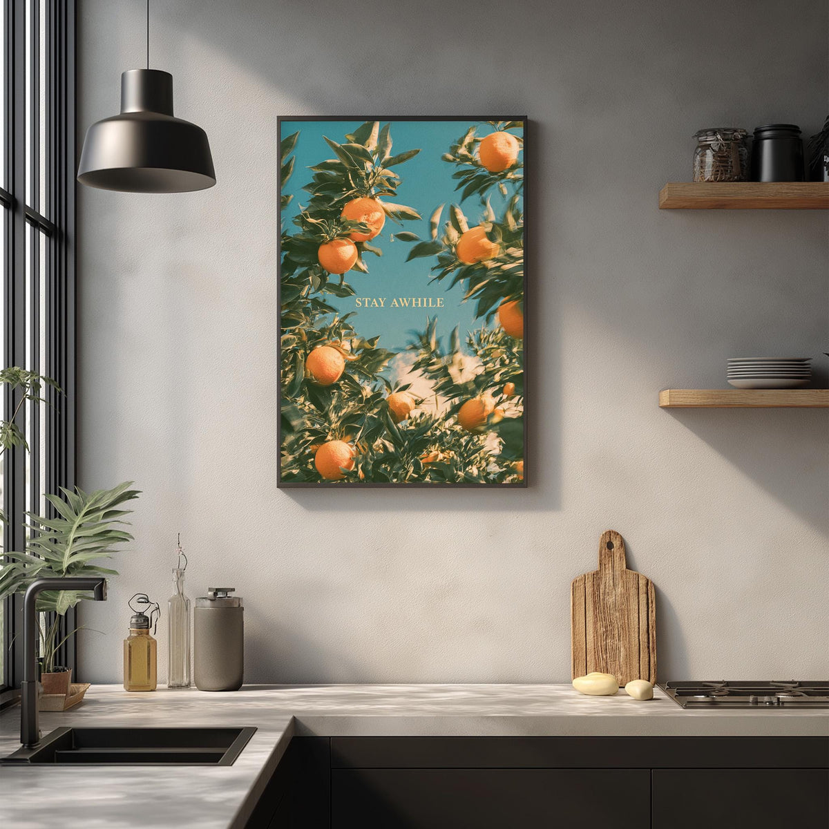 a kitchen counter with a framed poster of an orange tree hanging above it. The poster has the text "STAY AWAY" written on it. The kitchen counter also has various items such as a cutting board, a bottle, and a bowl.