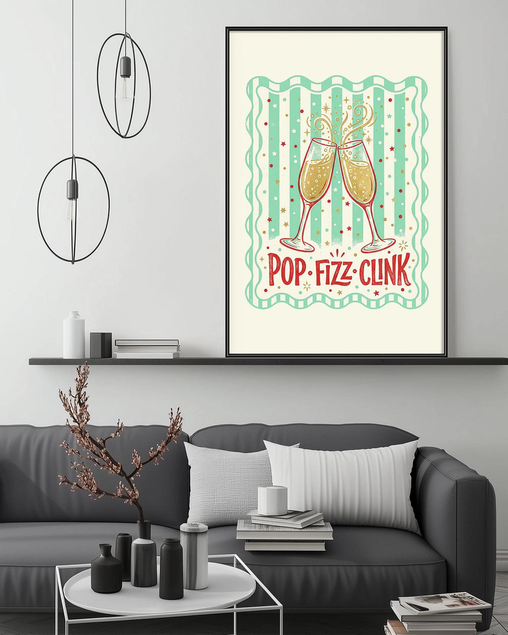 a living room with a gray couch, a coffee table, and a framed poster on the wall. The poster has a design of champagne glasses and the text "POP-FIZZ-CLINK" written on it.