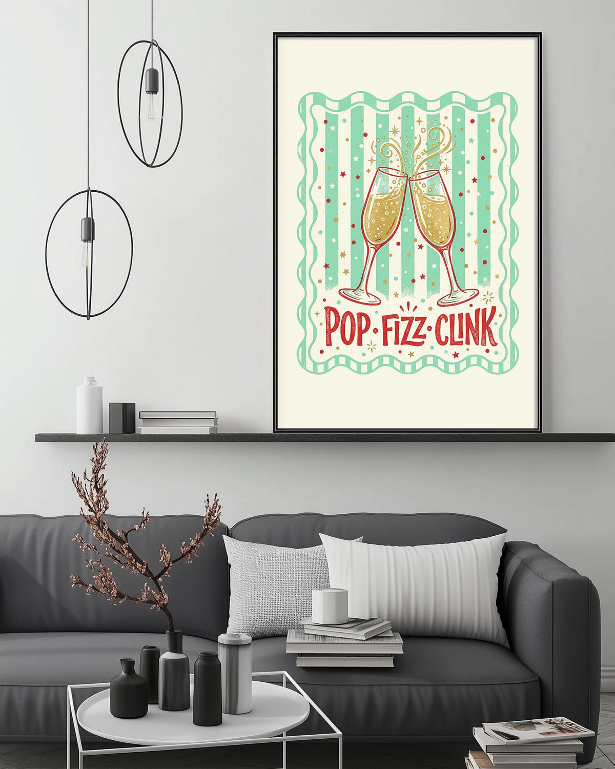 a living room with a gray couch, a coffee table, and a framed poster on the wall. The poster has a design of champagne glasses and the text "POP-FIZZ-CLINK" written on it.