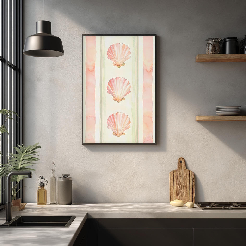 a kitchen counter with a framed picture of three pink seashells hanging above it. The kitchen counter also has various kitchen items such as a cutting board, a bottle, and a bowl.