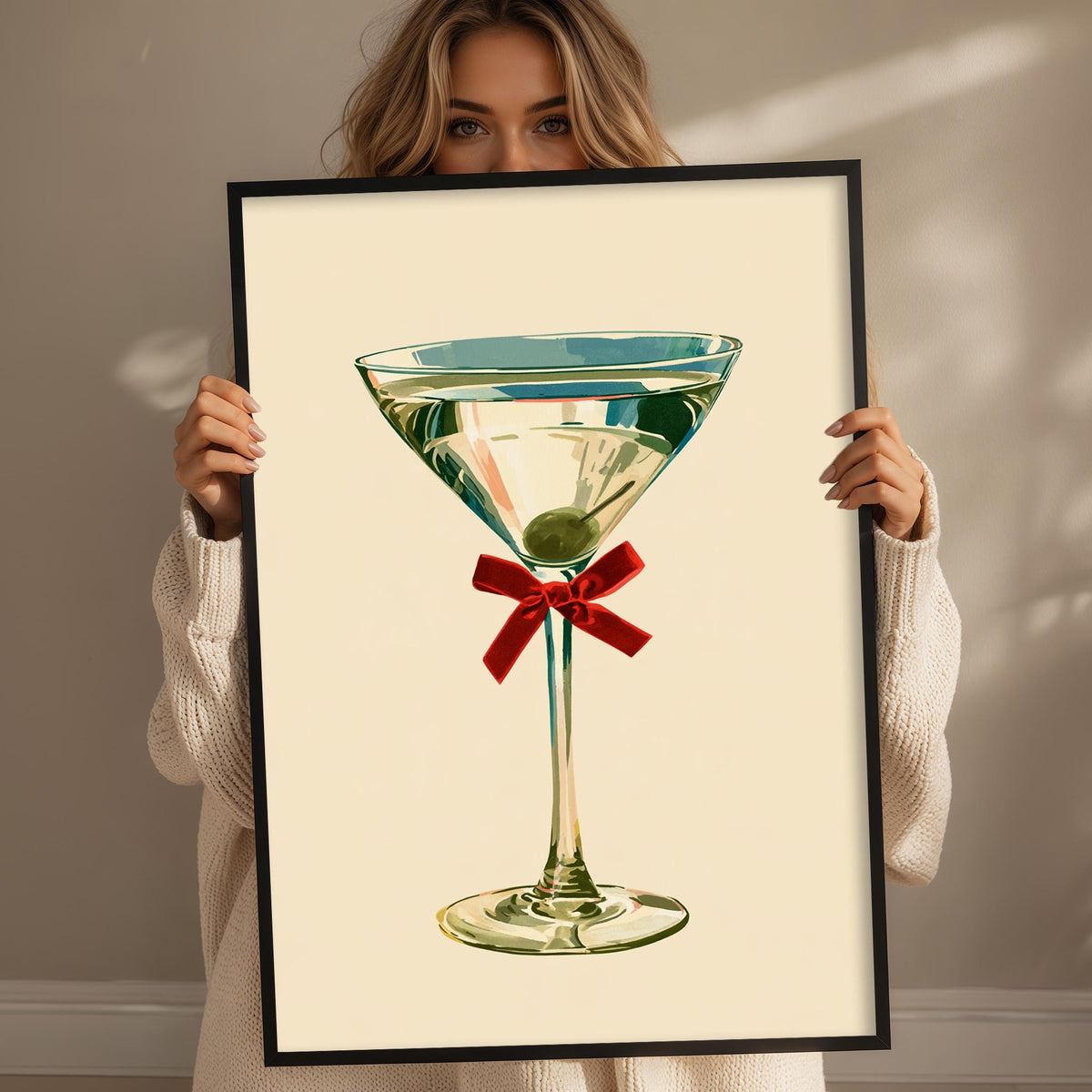 A woman holding a framed picture of a martini glass with a red ribbon.