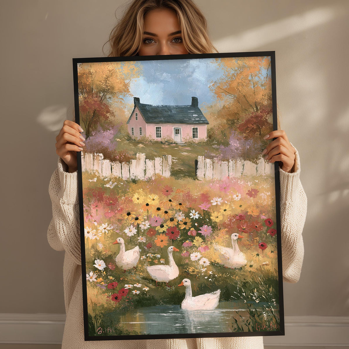 A woman holds up a framed painting depicting a serene garden scene with a house, flowers, and ducks swimming in a pond.
