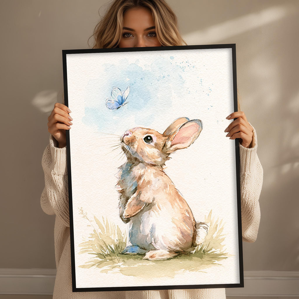 A woman holds up a framed painting of a rabbit in a grassy field, gazing up at a butterfly in the air.