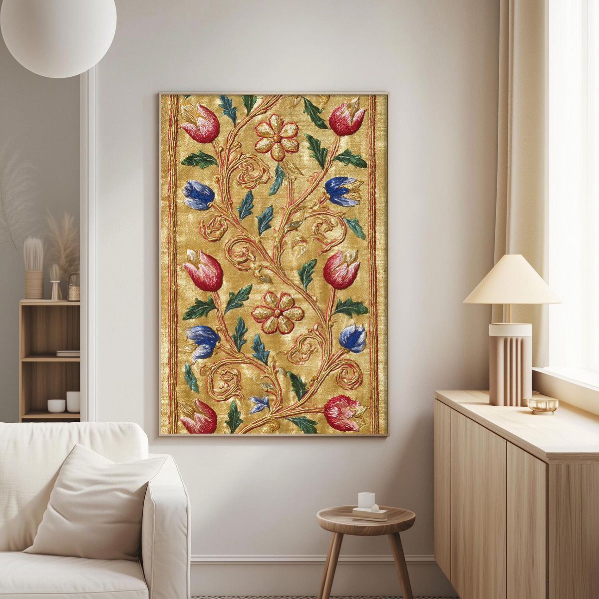 a living room with a large, ornate gold and red floral tapestry hanging on the wall. The tapestry is adorned with various flowers and leaves, creating a vibrant and intricate design. The room also includes a white sofa, a wooden side table, and a lamp, contributing to a cozy and inviting atmosphere.