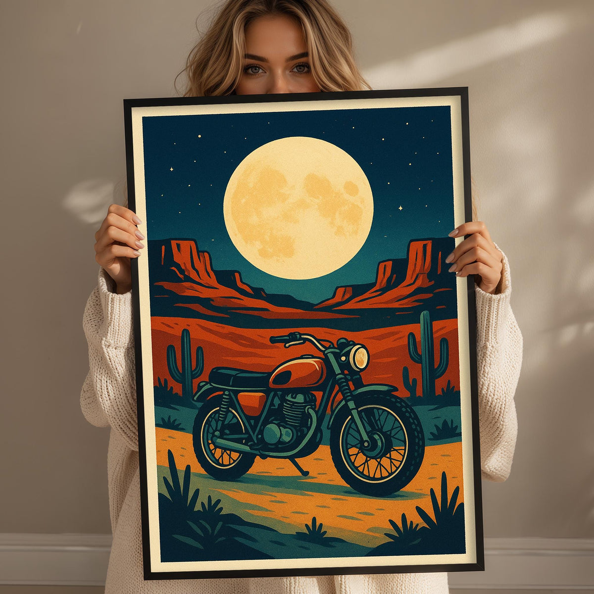 A woman holds up a framed poster depicting a motorcycle on a desert road under a large, bright moon.