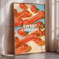 a poster with a vibrant design of red and orange fruits, including apples and carrots, arranged in a visually appealing manner. The poster is framed and placed on a wall, creating a striking and eye-catching display.