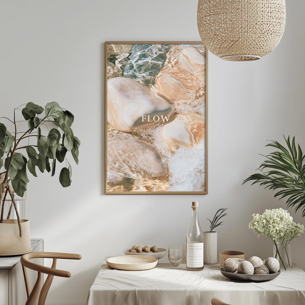 a dining table with a bowl of fruit, a bottle, and a vase of flowers, along with a framed picture hanging on the wall above the table.