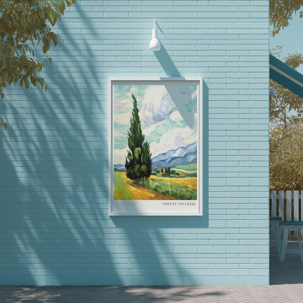 a framed painting of a landscape with a tall tree in the foreground, set against a blue brick wall.